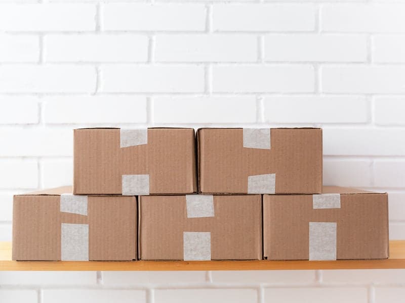 A neat stack of cardboard boxes on a wooden shelf